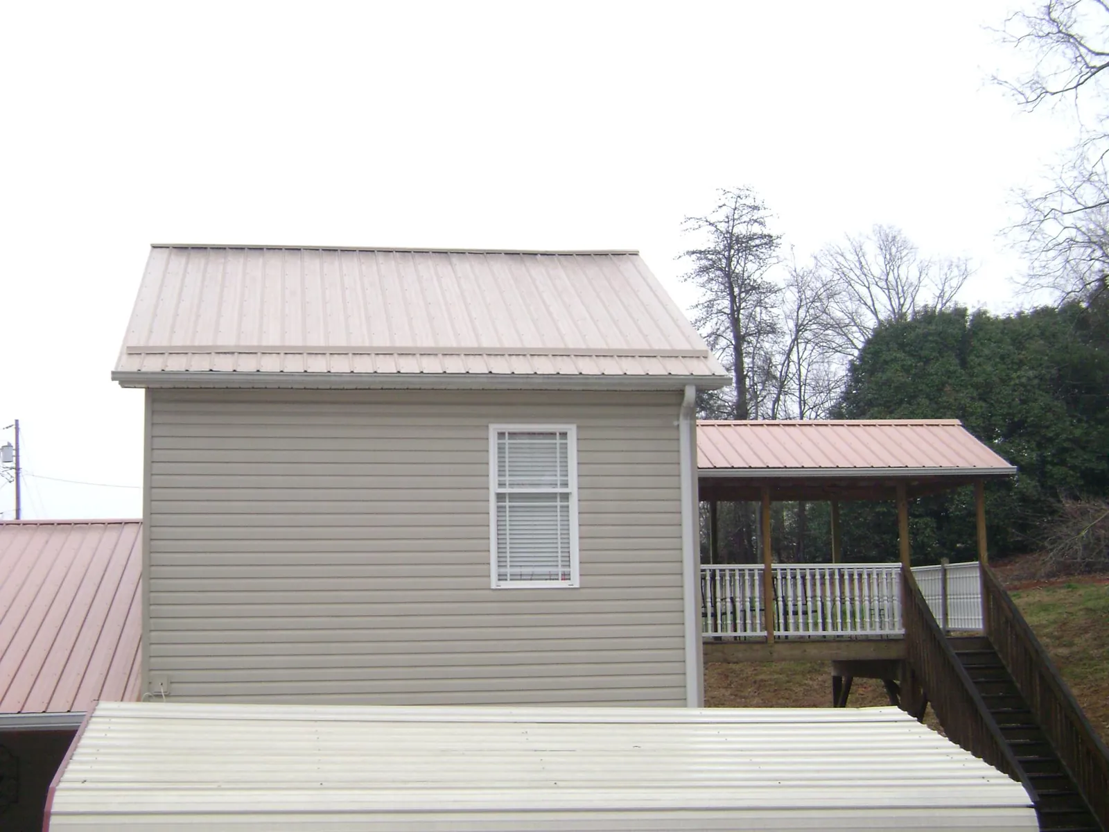 Tan metal roofs on a two story addition and attached porch, from a Roof Replacement job in Clarksburg